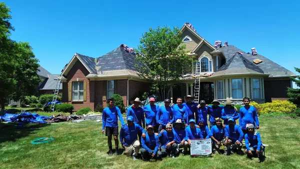 The DV Dependable Roofing crew in blue uniforms in front of a finished brick home