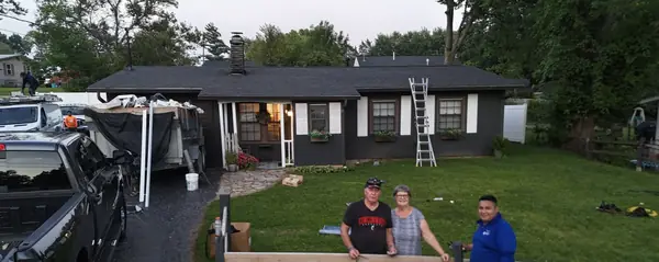 Homeowners standing with a DV Dependable Roofing crew member after the job