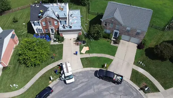 Drone view of the crew re-roofing a two-story colonial home in a cul-de-sac