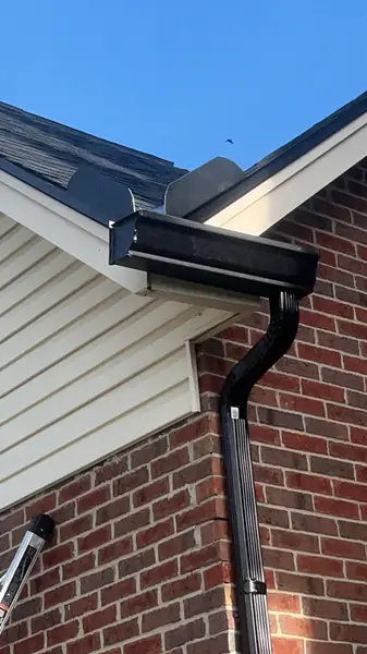 Black seamless aluminum gutter and downspout on a brick and siding home