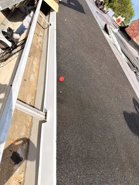 Built-in box gutter opened up for restoration beside a flat roof section