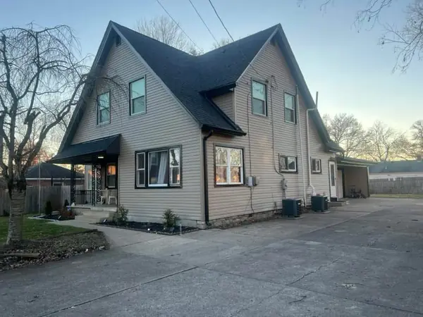 Cape cod home with a new black shingle roof and tan siding at sunset