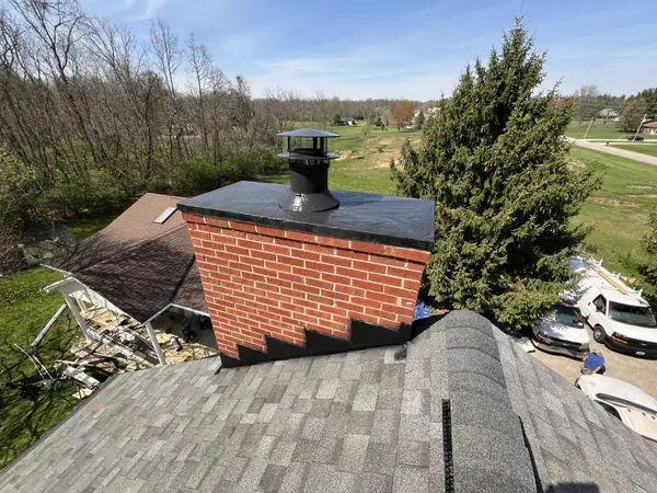 Brick chimney with a new cap and flashing on a freshly shingled roof