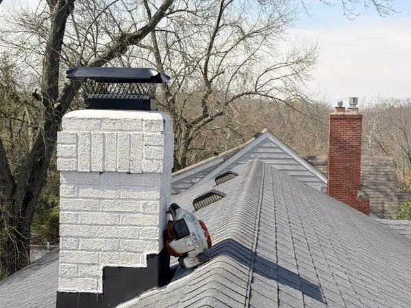 Painted brick chimney with a new black chimney cap and flashing