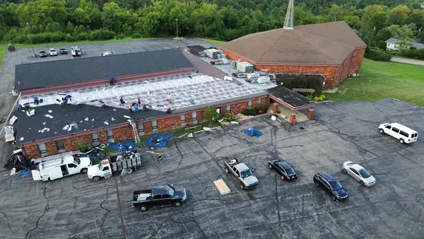 Drone view of a long commercial building roof replacement and parking lot