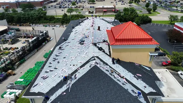 Drone view of a commercial building roof replacement next to a red metal roof