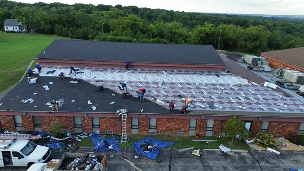 Roofing crew installing shingles on a commercial building