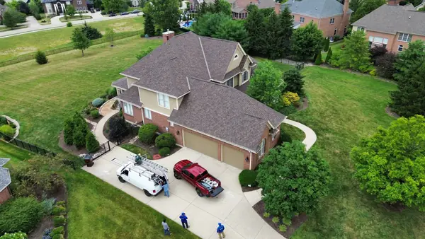 Drone view of a completed architectural shingle roof on a suburban home