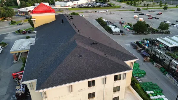 Drone view of a finished dark shingle roof on a multi-story commercial building