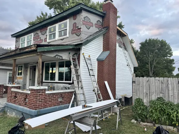 Vinyl siding being installed on a craftsman bungalow with a brick chimney