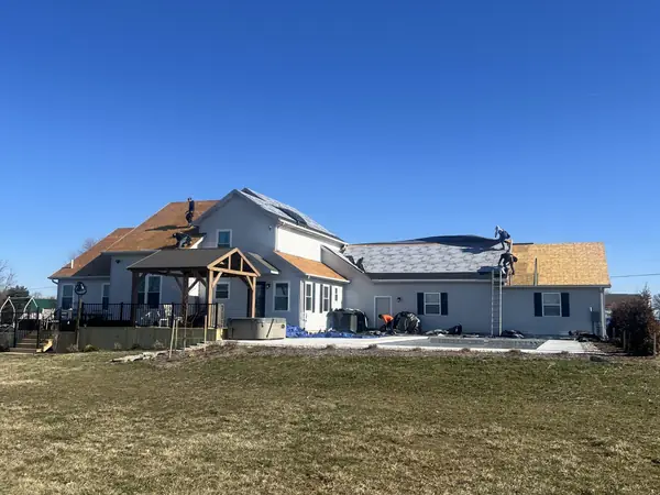 Crew replacing the roof on a large farmhouse with a timber-frame porch