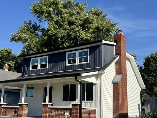 Craftsman home with navy board and batten dormer, white siding and brick chimney