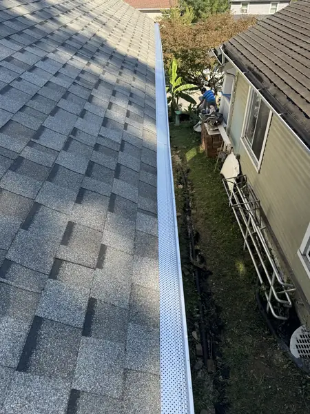 Gutter guards installed along the eave of a gray shingle roof