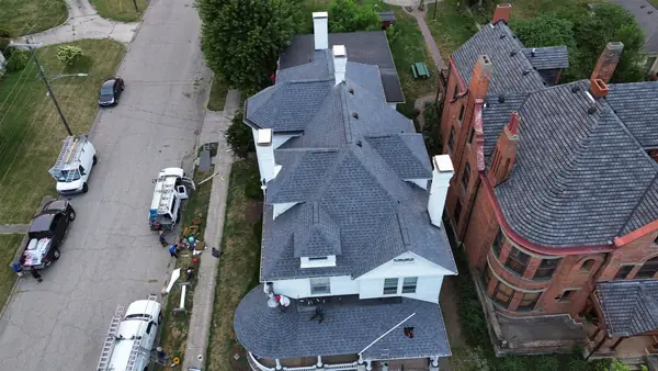 Aerial view of a historic Victorian home roof beside a brick mansion