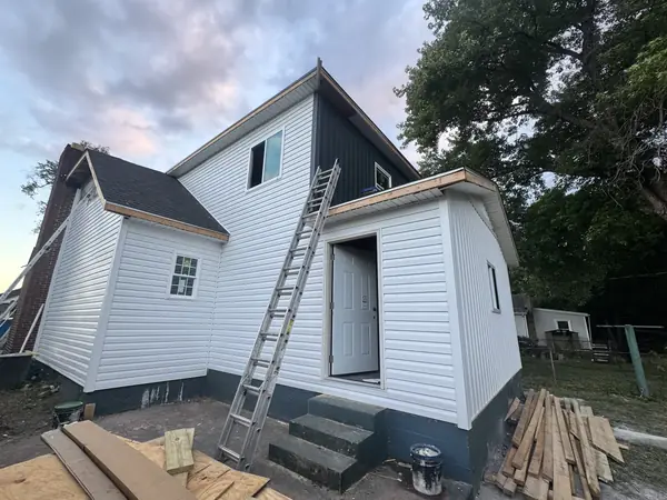 New home addition finished in white siding with a side entry door