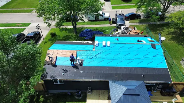 Low-slope roof covered in blue synthetic underlayment during replacement