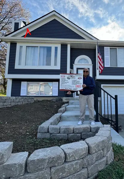 Split-level home finished in navy siding with white trim and a stone walkway