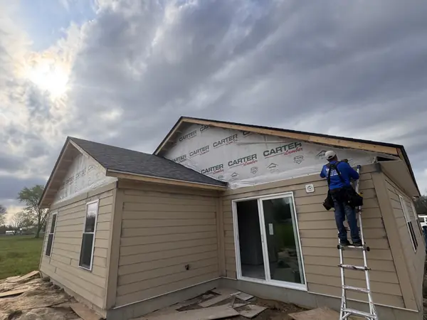 New home addition in tan lap siding with house wrap on the upper gable