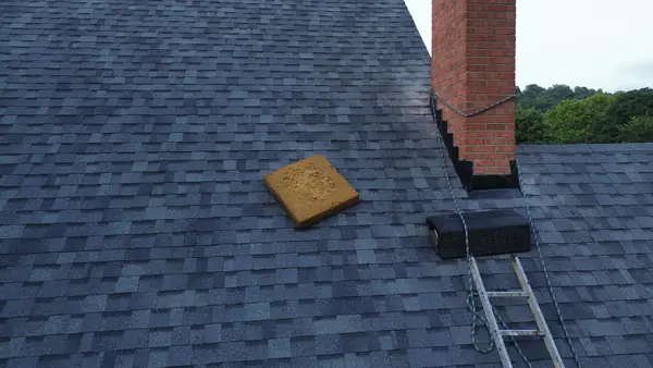 New gray shingles with fresh flashing around a brick chimney