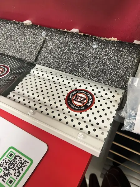Perforated aluminum gutter guard sample installed under shingles, available in any color