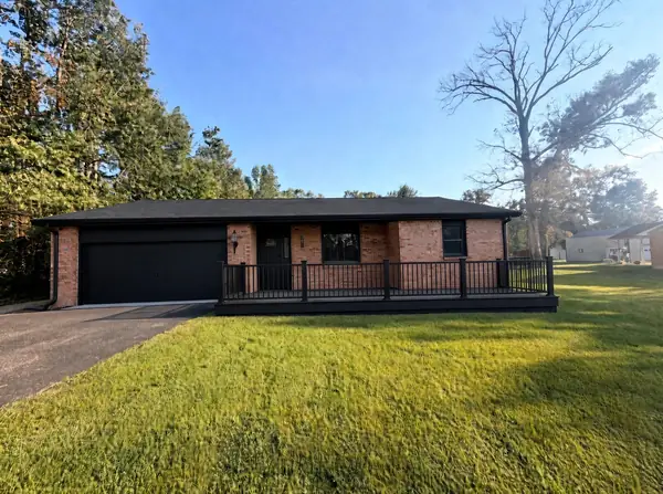 Brick ranch with a new dark roof, black garage door and a new porch railing