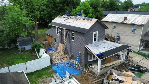 Aerial view of roofing and siding crews working on a two-story home