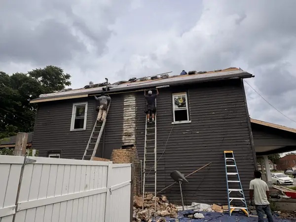 Crew removing old roofing and siding from a two-story home