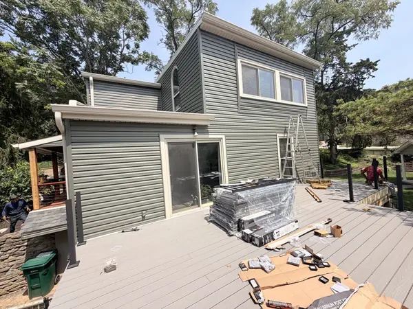Contemporary home re-sided in sage green vinyl above a composite deck