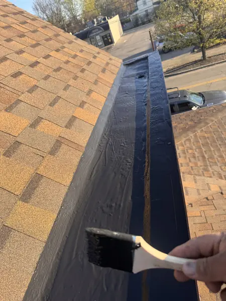Technician brushing sealant into a built-in box gutter