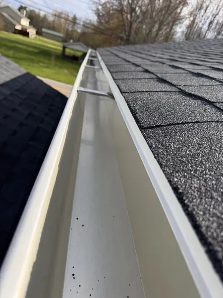 Seamless gutter running straight along a new architectural shingle roofline