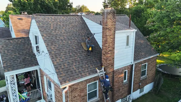 Roofer on a brick home re-roof with a tall brick chimney