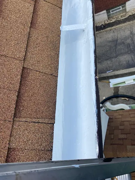 Built-in box gutter sealed with a bright white silicone coating along the shingle edge