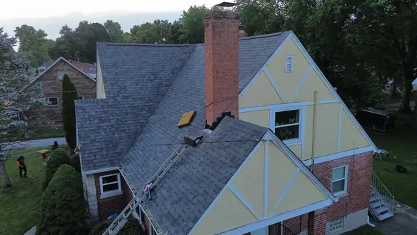 Roof replacement on a Tudor-style home with a tall brick chimney
