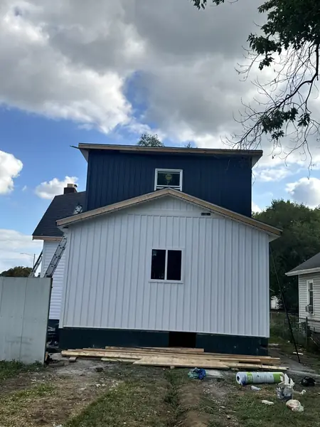 White board and batten siding below a navy upper story on a remodeled home