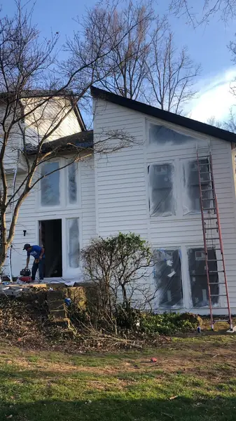 Contemporary two-story home getting new white siding with windows masked