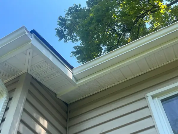 New white vented soffit, aluminum fascia and gutter at an outside roof corner